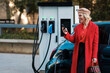 © Malquerida Studio/Stocksy - Woman browsing smartphone while recharging electric car