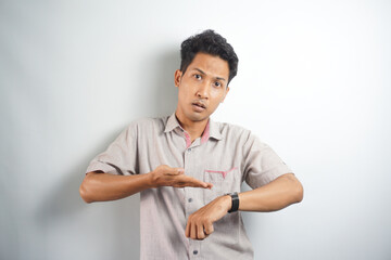 Handsome asian man wearing casual shirt In hurry pointing to watch time, impatience, upset and angry for deadline delay