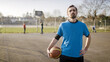 Portrait of basketball player looking to caerma whilst on an outdoor court, with space for text