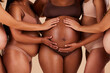 © Lumeez/peopleimages.com - Women, hands or touching pregnancy stomach of black woman on studio background in growth support, love or community. Zoom, body or friends in pregnant underwear and belly feeling for baby health kick