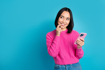 Poster - Portrait of pretty cute indonesian girl finger touch lip hold telephone look empty space isolated on blue color background