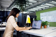 © Cavan Images - Side view of businesswoman using laptop at desk in creative office