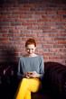 © Cavan Images - Happy businesswoman using smart phone while sitting on couch at office lobby