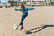 © Ivan Gener/Stocksy - Boy kicking a soccer ball on a beach