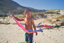 Boy With Down Syndrome In Denim Shorts Playing With Kite On Beach