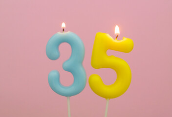 Birthday candles burning on pink background, number 35