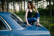 © Cavan Images - Young hipster woman sitting on a blue vintage car.