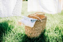 Wicker Basket Filled With Bed Linen In A Yard At Home In Summer