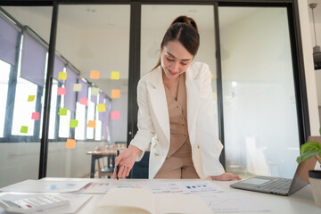 Asian businesswoman reading a report document during working on a laptop in an office