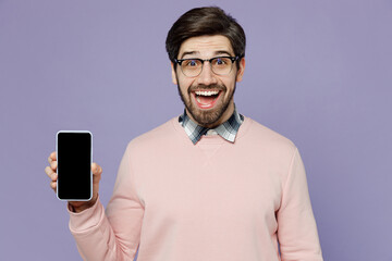 Young surprised IT man he wear casual clothes pink sweater glasses hold in hand use mobile cell phone with blank screen workspace area isolated on plain pastel light purple background studio portrait.