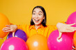 Happy fun amazed surprised shocked impressed young woman wearing casual clothes celebrating among balloons look aside on area isolated on plain yellow background. Birthday 8 14 holiday party concept.