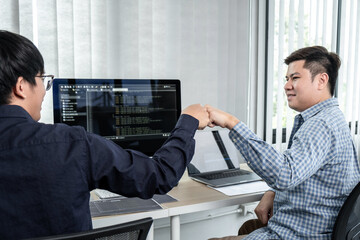 Wall Mural - Team of two professional programmers working on website projects in software development and making a fist-bump after mission complete making coding and typing data code password security in office