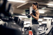 © dusanpetkovic1 - A strong sportswoman is lifting dumbbells in a gym and doing exercises for biceps.