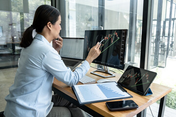 Wall Mural - Businesswoman investor having planning a new project and analyzing graph data with display screen the data presented and deal on a stock exchange