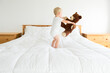 © Cavan Images - Cute boy playing with teddy bear while standing on bed