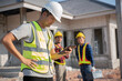 © Attasit - Engineer construction and two safety suit workers at a building site with a home construction