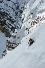 A Man Skiing Down A Steep Mountain In The Tetons Outside Of Jackson, Wyoming.