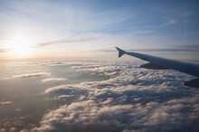 Aerial View Of Airplane Flying Over Clouds At Sunset