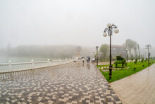 Beautiful Wet And Foggy Embankment With People Walking Under Umbrellas. Foggy Rainy Autumn Landscape With Modern Park In Zheleznovodsk.