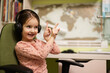 © AS Photo Family - Young girl wearing headphones, enjoys her remote education. Distant studying, homeschooling. Show fingers up.