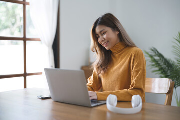 Asian business woman using headphone and laptop video conference meeting online work at home.