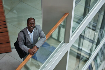 Poster - Mature African American businessman in grey suit looking at camera with smile while standing by transparent railing in office center
