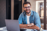 Portrait of attractive smiling man sitting in office and looking at camera.