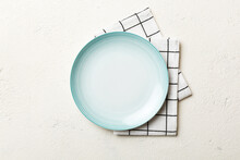 Top View On Colored Background Empty Round Blue Plate On Tablecloth For Food. Empty Dish On Napkin With Space For Your Design