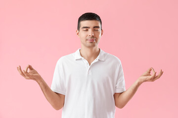 Wall Mural - Young guy meditating on pink background