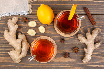 Glass cups of black tea, sliced ginger root, lemon and anise on wooden table