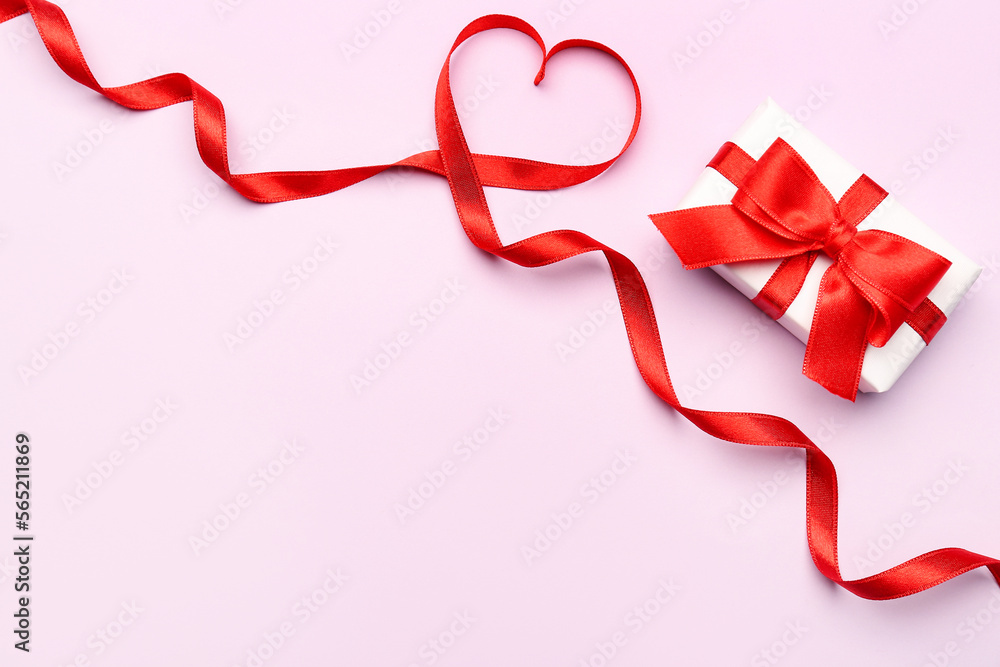 Gift and heart made of red satin ribbon on pink background. Valentine's Day celebration