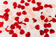 White surface covered with multiple red and pink heart shaped paper confetti, top view