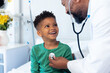 © wavebreak3 - African american male doctor using stethoscope on smiling boy patient in hospital