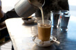 © Cavan Images - Hot milk is poured into coffee at a cafe in Asilah, Morocco.