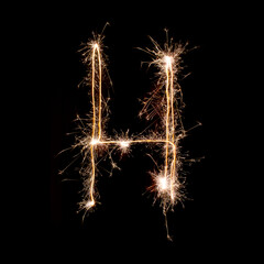 Sparkling burning creative letter H isolated on black background. Beautiful glowing golden overlay object for design holiday greeting card. Creative lettering H written with burning sparklers