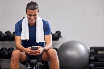 Fitness, phone or man on social media to relax at gym in training, workout or exercise resting on a break. Tired, happy or healthy sports athlete typing text on a bench and exercising for body goals