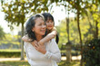 © Prathankarnpap - Smiling mature grandmother giving piggyback ride to cute little granddaughter during walking on in the park