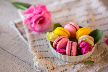 Wall Mural - Good morning. Delicious macarons desserts are served on the table in the morning for breakfast. Beautiful light still life with a rose highlight. Baking for breakfast on a light table with copy space