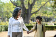 © Prathankarnpap - Smiling grandmother and her little grandchild walking together surrounded by trees during sunny day