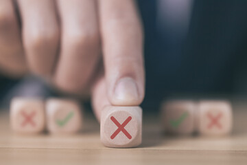 Businessman touching wooden block showing wrong sign, wooden block showing both right and wrong decision concept