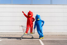 Man And Woman Wearing Duck Costumes Standing With Shopping Cart In Front Of Wall