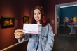 © EdNurg - Visitor holding ticket to fine art museum with paintings. Art exhibition and entertainment