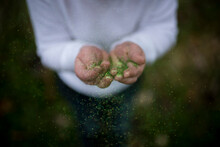 Midsection Of Boy Playing With Green Glitter While Standing In Yard