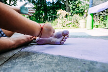 Child Playing Outside With Chalk Coloring Bottoms Of Feet In Sunlight