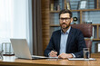 © Liubomir - Portrait of successful smiling man in office, mature businessman looking at camera cheerfully, senior boss in glasses and beard working inside office with laptop and documents, signing contract.