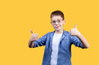 Portrait of a happy boy with glasses showing thumbs up. He’s smiling and looking at camera. Yellow background. Front view. Copy space. Suitable for collage and banner making and other design
