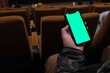over the shoulder of hand hold green screen phone in cinema
