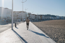 Young Athletic Black Man Running Along The Beachside In The Sun