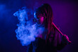 © Вероника Преображенс - A young woman with dreadlocks smokes a cigarette in a club. Wearing black glasses, he holds a painless bat in his hands. Girl with afro pigtails in the smoke at night in neon color. Scoundrel