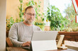 © annanahabed - Portrait of middle age man working from home, using portable computer and mobile phone